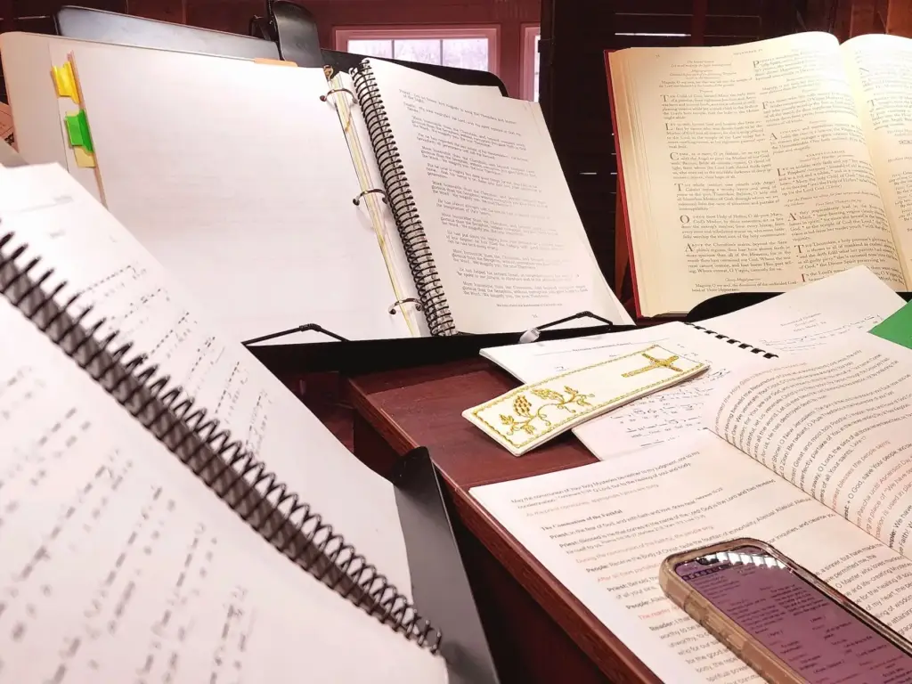 Stack of liturgical books and Byzantine hymns on a wooden chant stand.