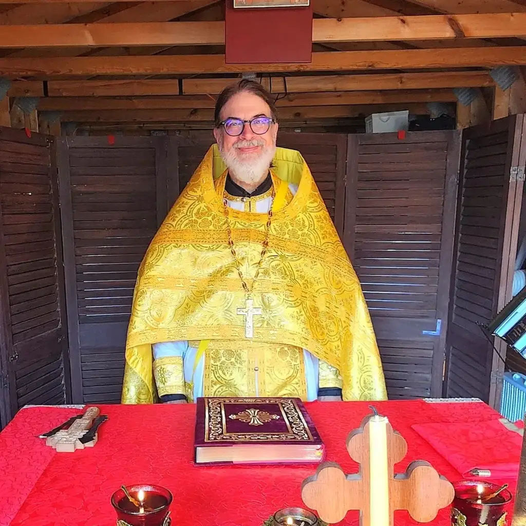 Father Gregory smiles and stands in the altar area in his vestments.