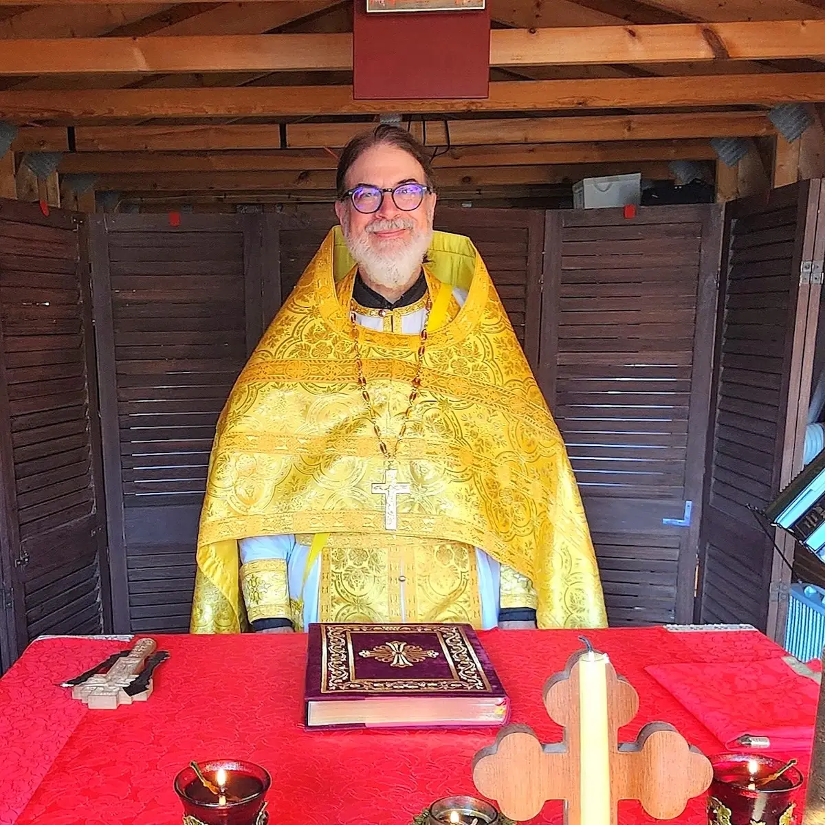 Father Gregory smiles and stands in the altar area in his vestments.