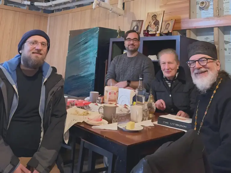 Parishioners and Father smiling for a photo after a fellowship gathering.