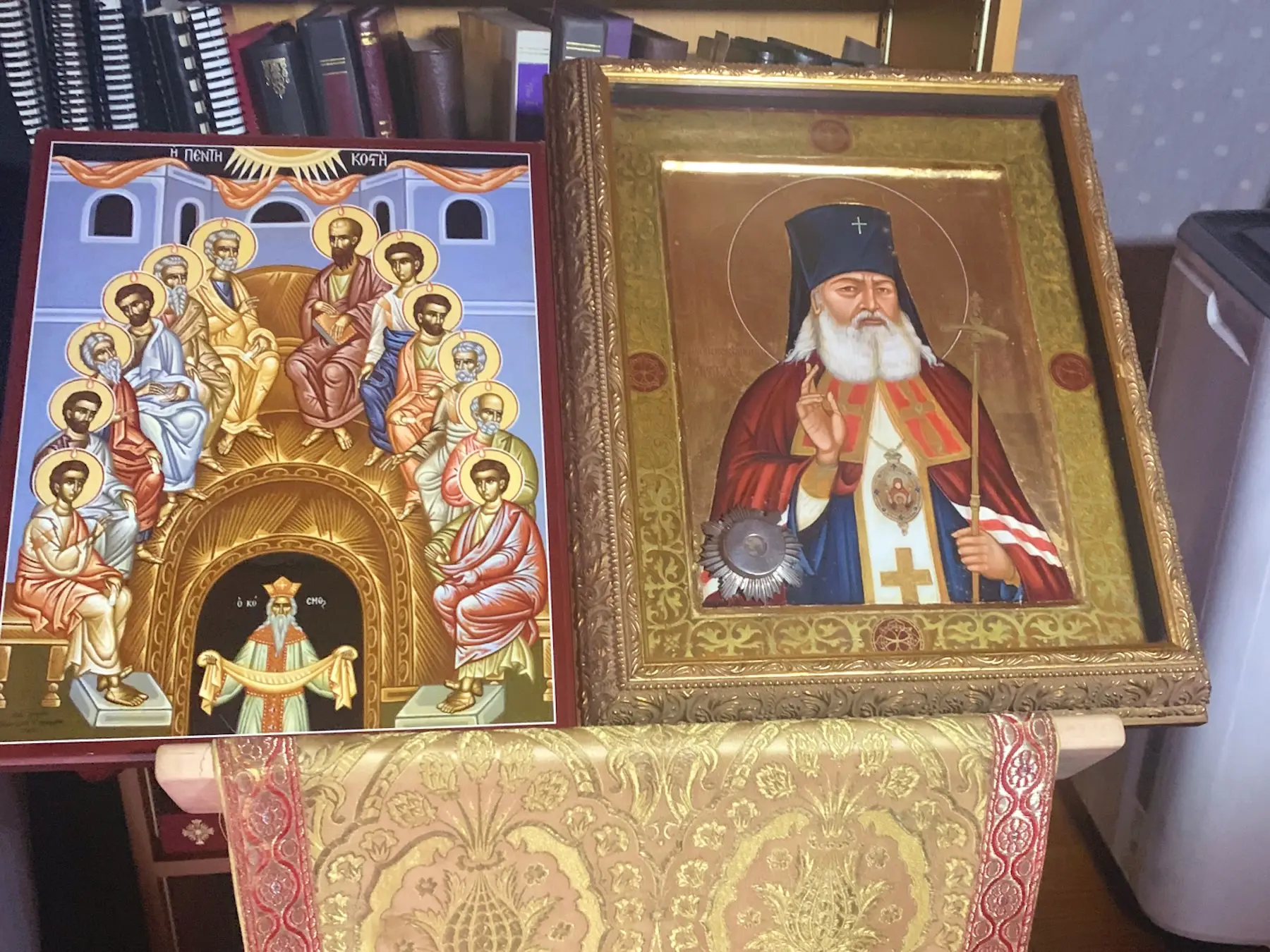 There are two icons resting on a stand. To the left is the icon of Pentecost. To the right is an icon of Saint Luke of Simferopol.