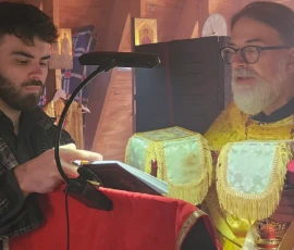The chanter holding a book for Father Gregory to read during a service.