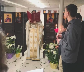 Father reading from the Gospel while the altar boys hold candles.