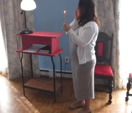 A woman holding a lit candle during a church service.