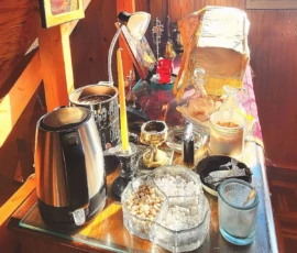 A side table in the altar with many liturgical items, including chalices for the Holy Gifts, an incense holder, and candles.