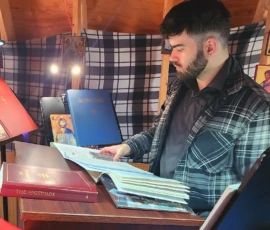 A chanter reads attentively from the Psalter during an Orthodox prayer service inside a small chapel space.