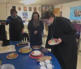 An Orthodox priest prepares to cut a blessed cake during a parish gathering following a church service.