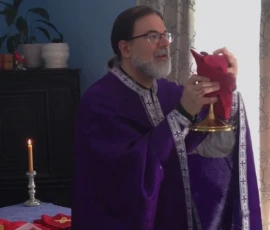 An Orthodox priest elevates the chalice during the Divine Liturgy while serving the Holy Eucharist in a reverent prayer setting.