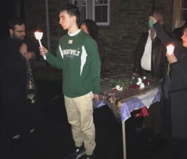 Faithful carry candles and the epitaphios during a Good Friday procession outside an Orthodox church at night.
