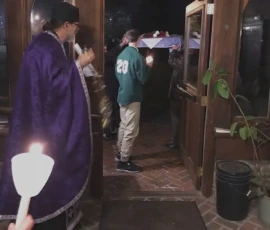 The clergy and faithful process with candles and the epitaphios through the church doorway during Holy Friday services.